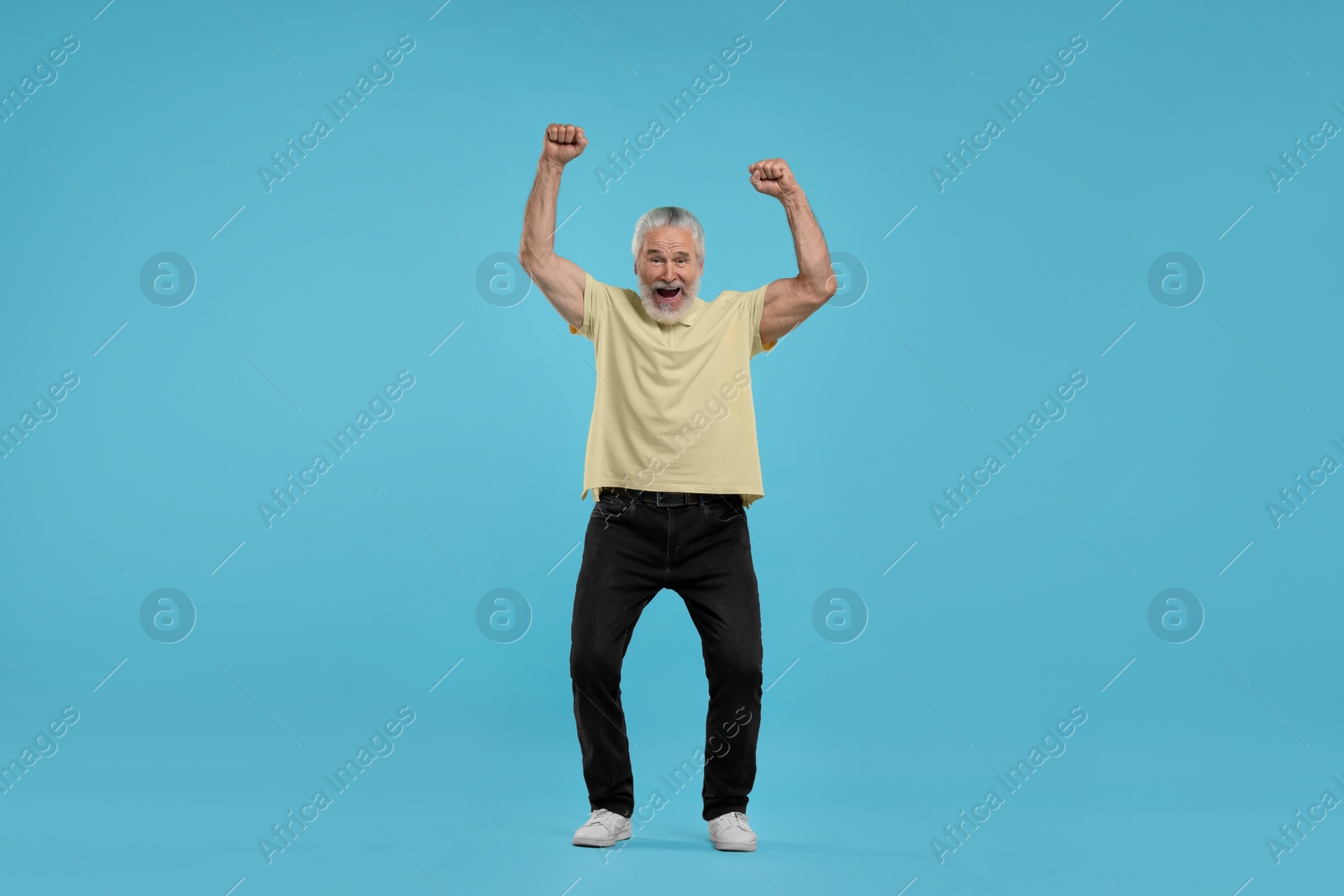 Photo of Emotional senior sports fan celebrating on light blue background