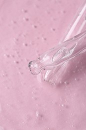 Photo of Pipettes with cosmetic serum on pink background, closeup