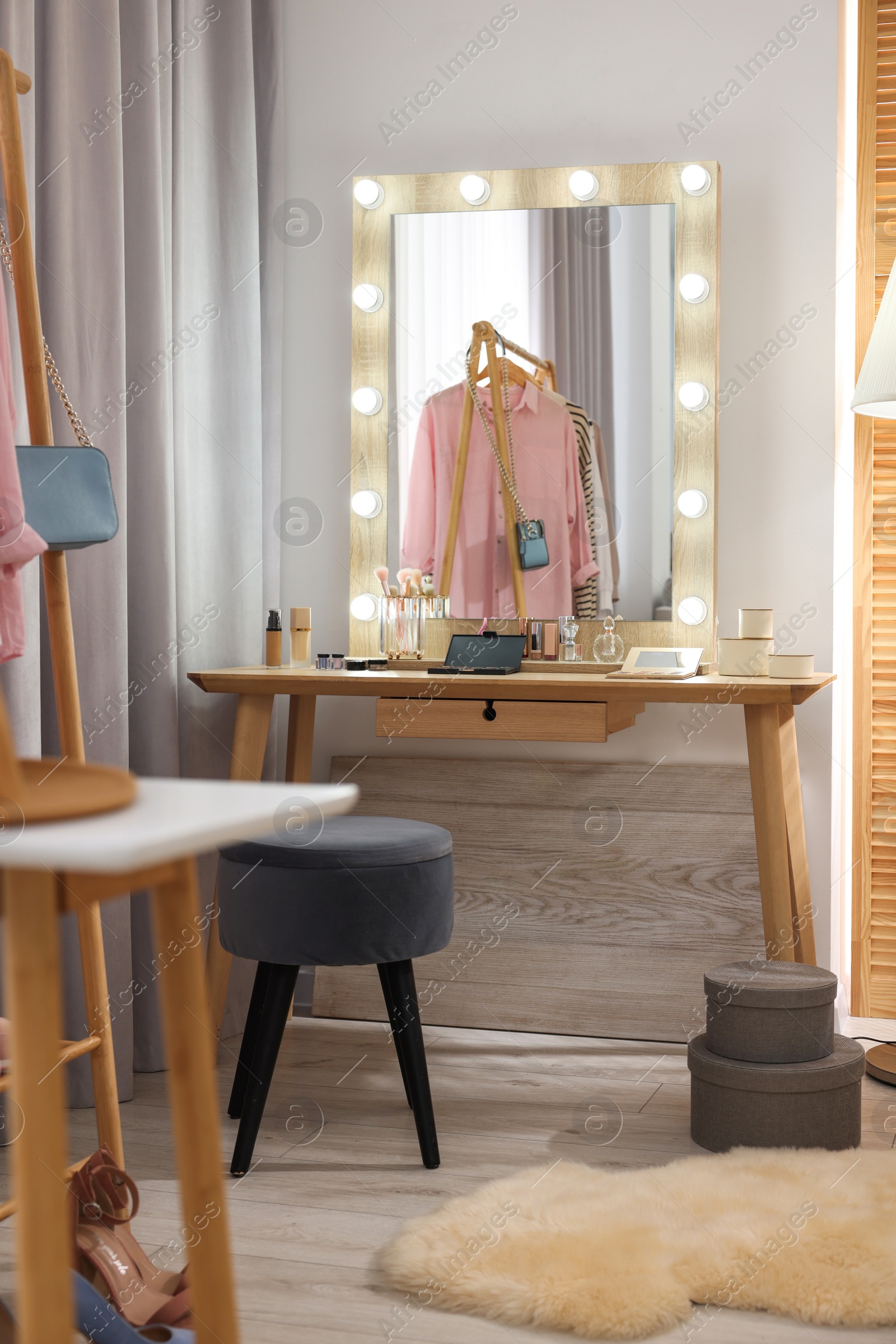Photo of Makeup room. Stylish wooden dressing table with mirror and chair indoors