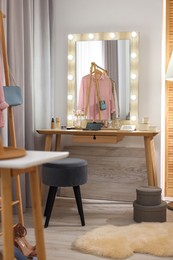 Photo of Makeup room. Stylish wooden dressing table with mirror and chair indoors