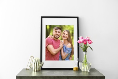 Image of Portrait of happy young couple in photo frame on table near white wall