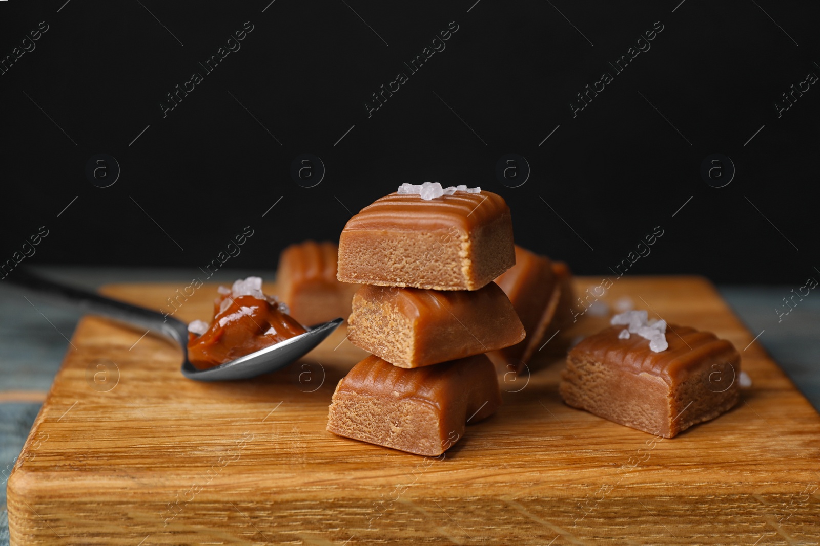 Photo of Delicious salted caramel on wooden board, closeup