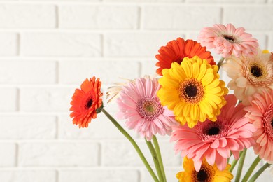 Photo of Bouquet of beautiful colorful gerbera flowers against white brick wall