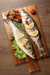 Photo of Delicious baked fish and vegetables on wooden table, top view