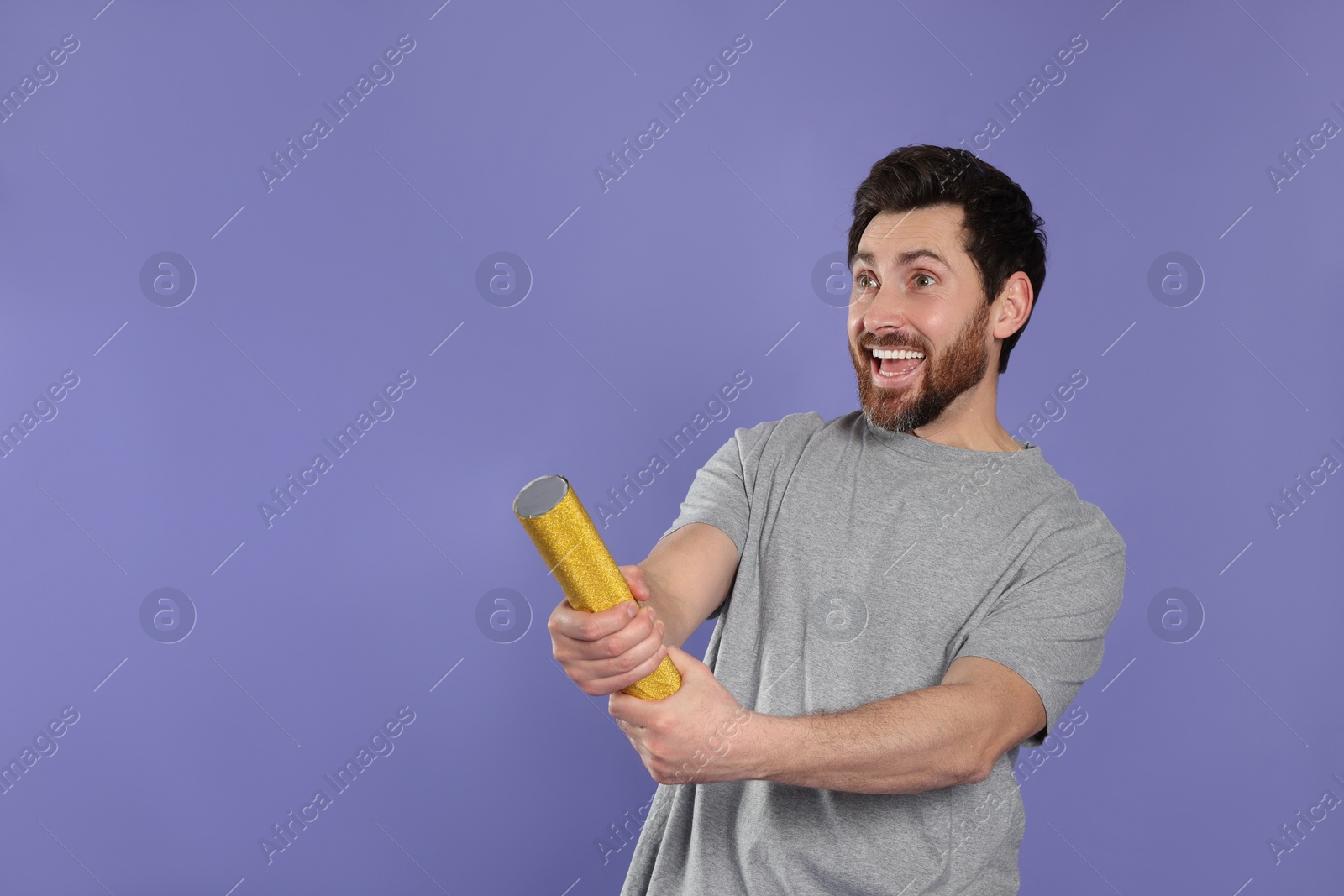 Photo of Emotional man with party popper on violet background. Space for text