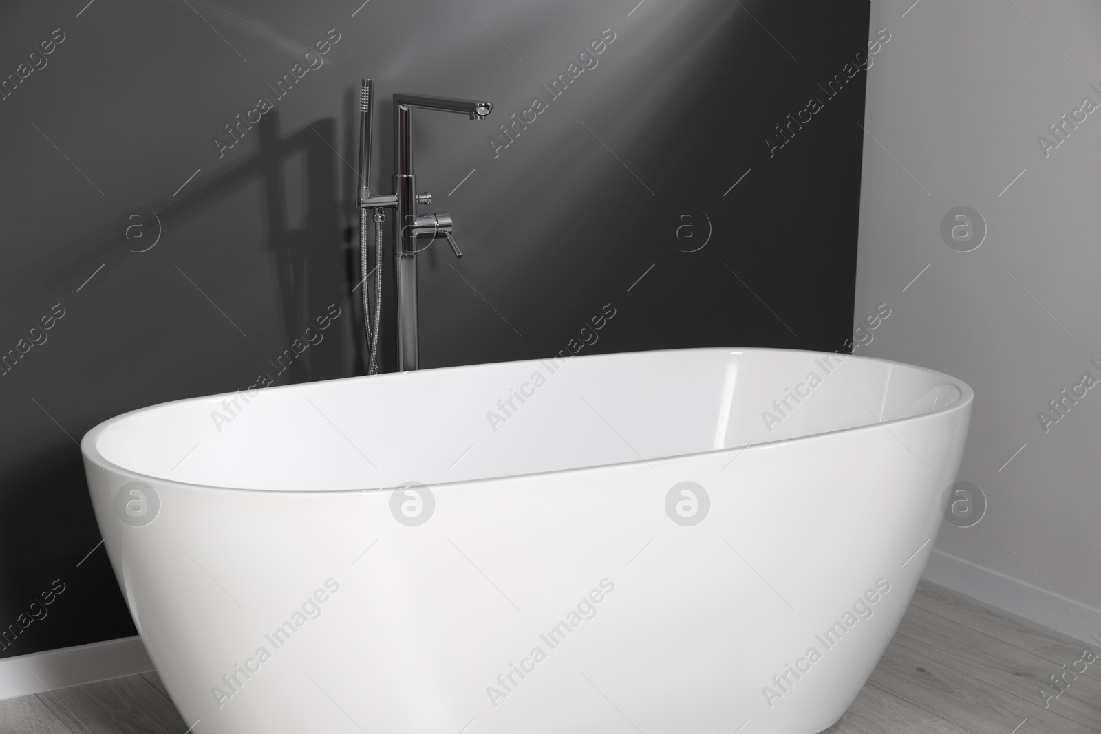 Photo of Stylish ceramic tub near grey wall in bathroom