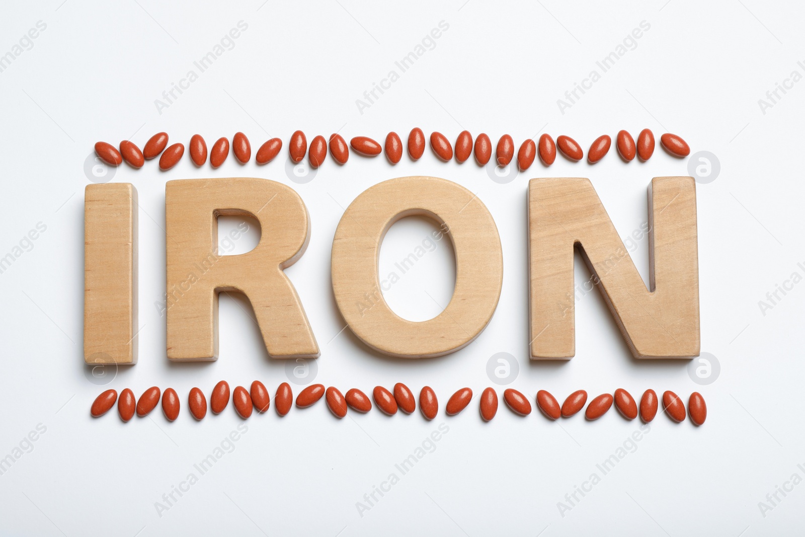 Photo of Word Iron and pills on white background, top view. Anemia concept
