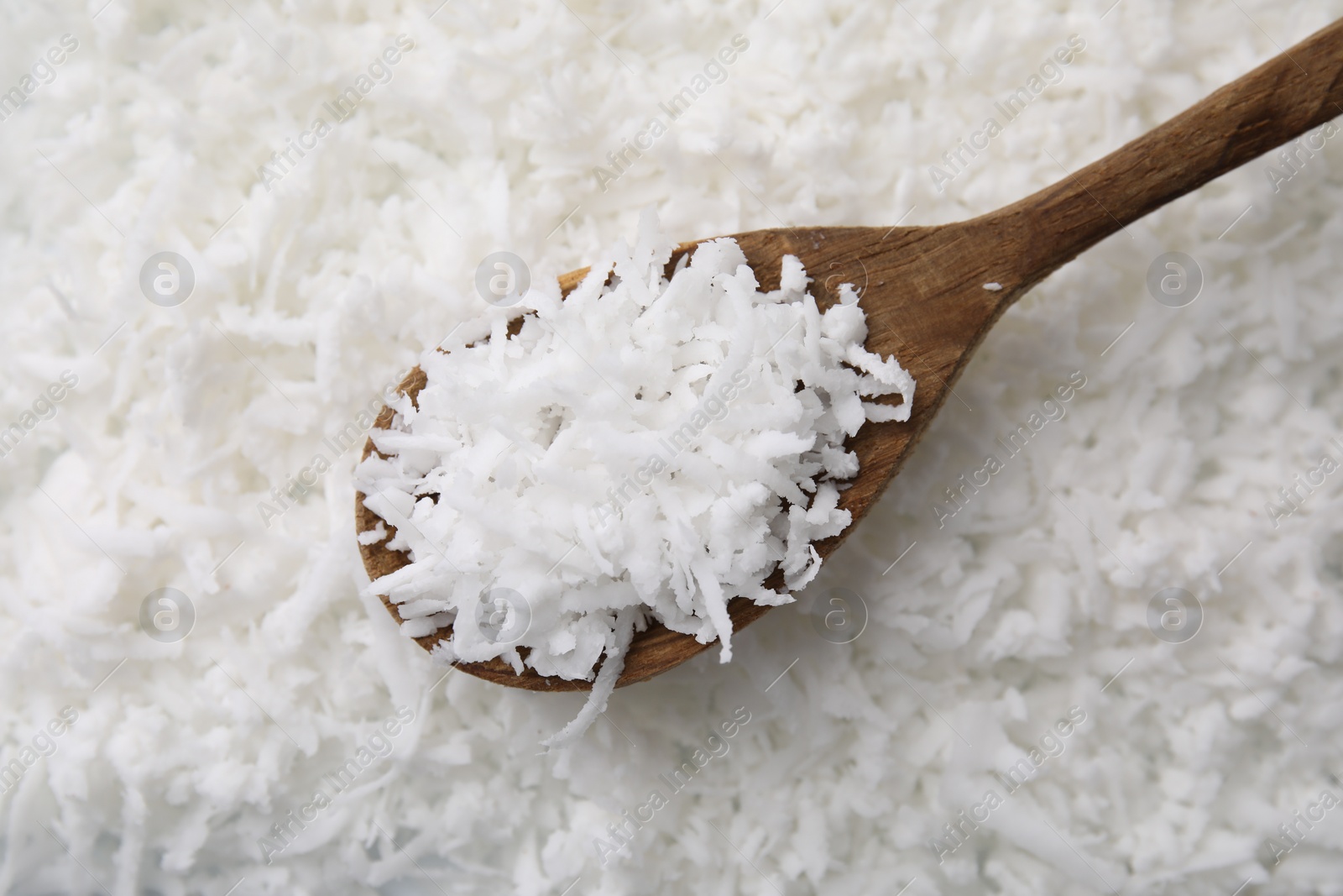 Photo of Fresh coconut flakes and wooden spoon, top view