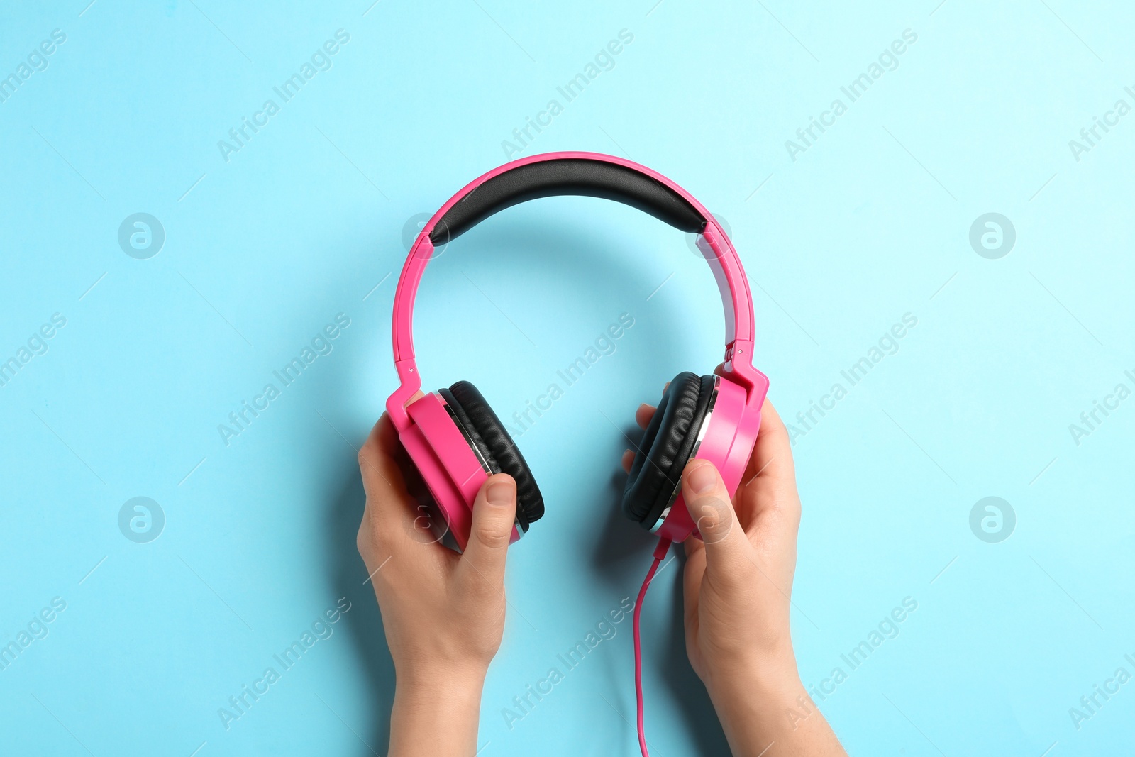 Photo of Woman holding stylish headphones on color background, closeup