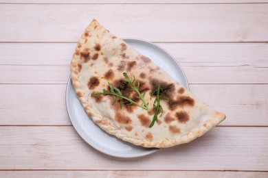Photo of Plate with delicious calzone on light wooden table, top view