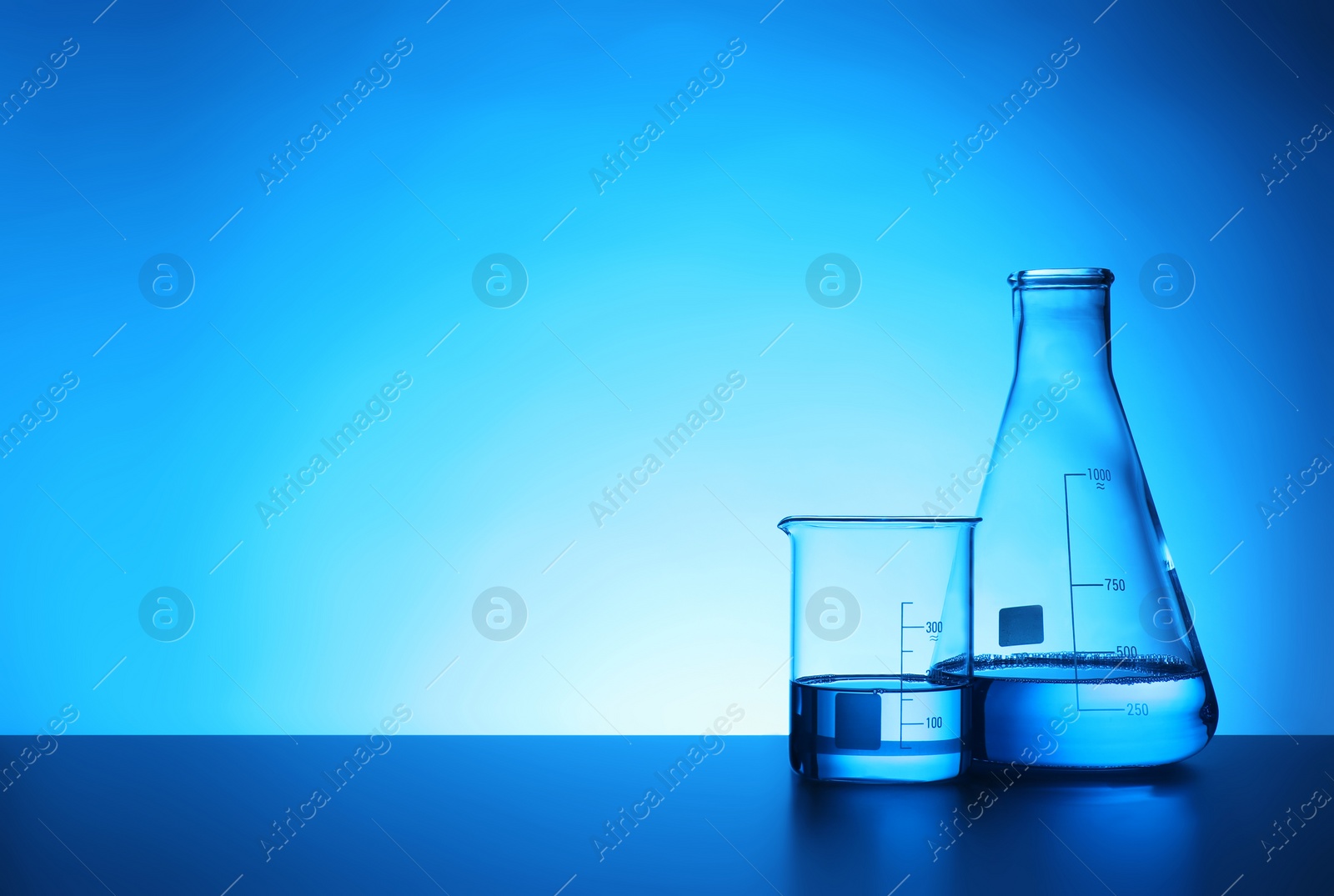 Photo of Chemistry laboratory glassware with samples on table against color background