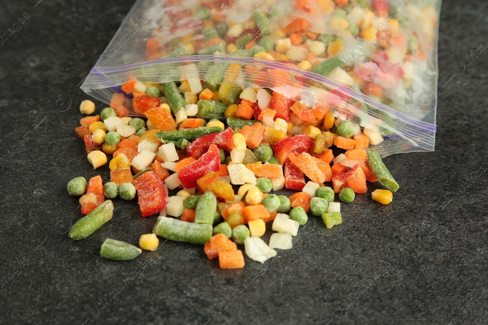 Photo of Zip bag with different frozen vegetables on grey table, closeup