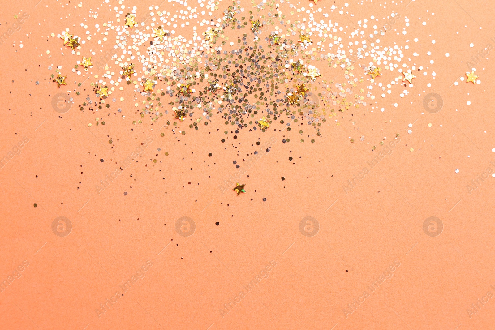 Photo of Shiny bright golden glitter on pale coral background, flat lay. Space for text