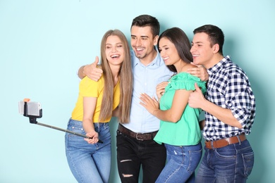 Young happy friends taking selfie against color background