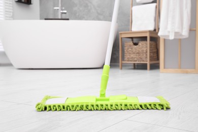 Cleaning dirty floor with mop in bathroom