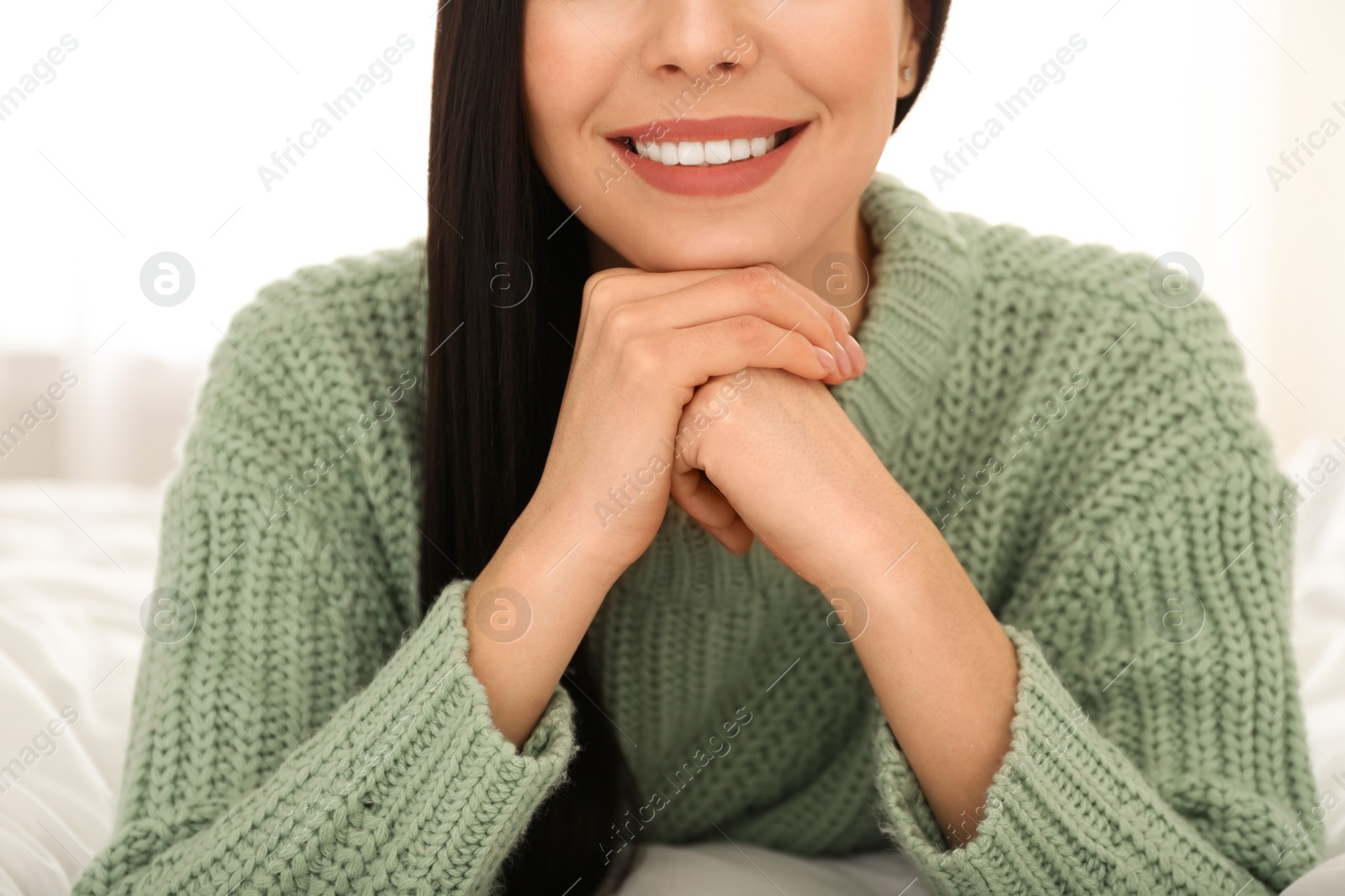 Photo of Young woman wearing warm sweater on bed at home, closeup. Winter season