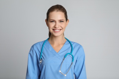 Portrait of young medical assistant with stethoscope on color background