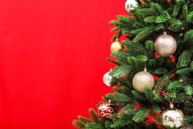 Beautifully decorated Christmas tree against color background, closeup