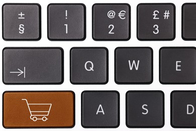 Image of Internet store. Brown button with shopping cart on computer keyboard, top view