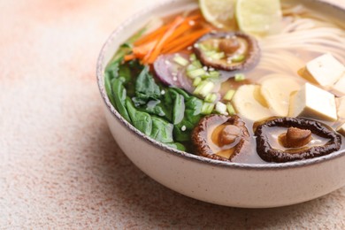 Photo of Bowl of vegetarian ramen on color textured table, closeup