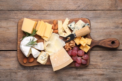 Photo of Cheese plate with grapes and nuts on wooden table, top view
