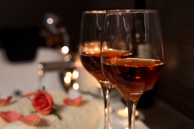Photo of Glasses of wine on tub in bathroom, closeup with space for text. Romantic atmosphere