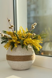 Beautiful mimosa flowers in vase on window sill indoors