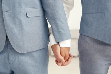 Photo of Newlywed gay couple holding hands at home, closeup