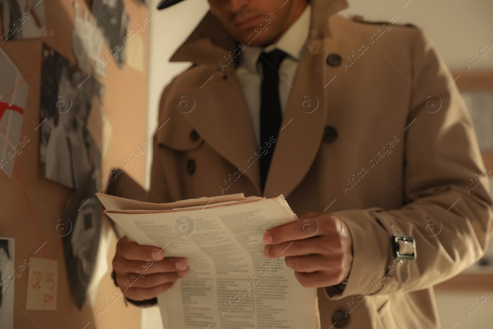 Photo of Detective with newspaper near evidence board in office, closeup