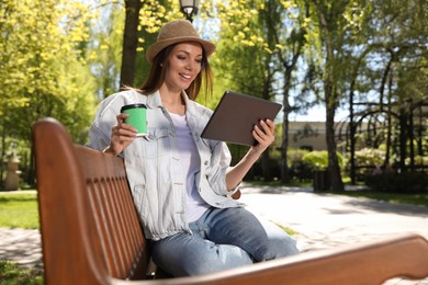 Photo of Woman with cup of coffee and tablet working in park
