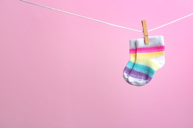 Photo of Small socks hanging on washing line against color background, space for text. Baby accessories