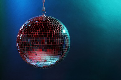 Photo of Shiny disco ball under blue lights, space for text