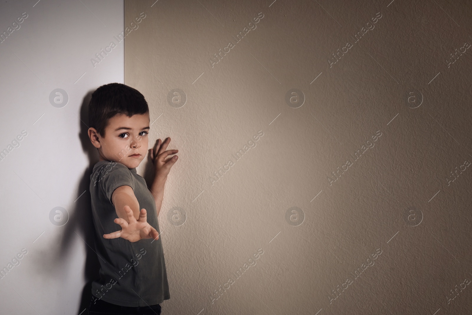 Photo of Little boy in corner near yellow wall, space for text. Child in danger