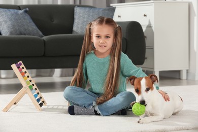 Cute girl playing with her dog on floor at home. Adorable pet