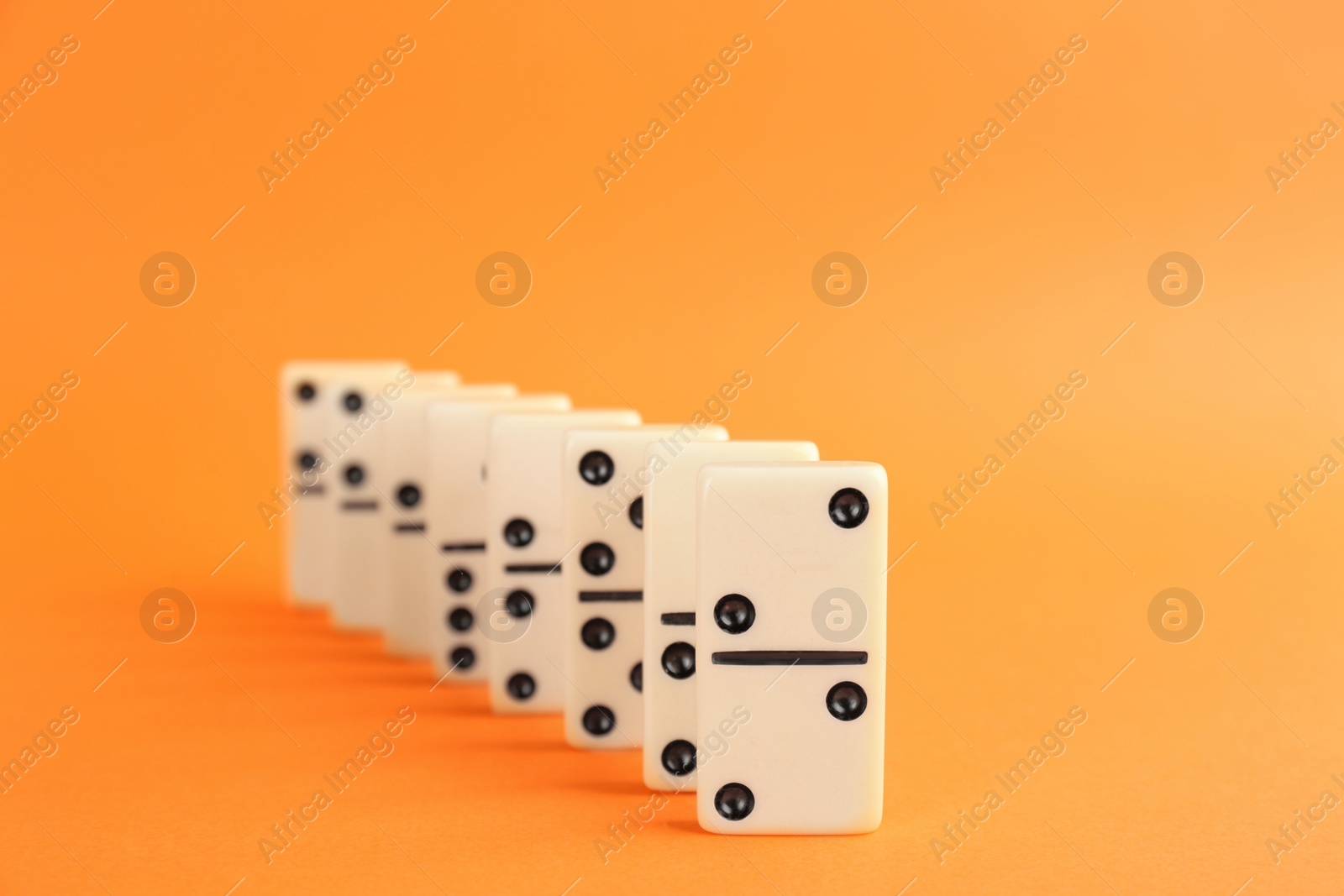 Photo of White domino tiles with black pips on orange background