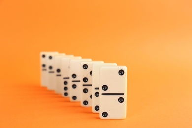 Photo of White domino tiles with black pips on orange background