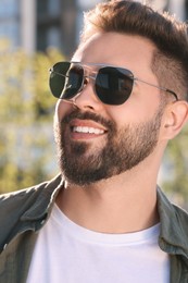 Photo of Handsome smiling man in sunglasses outdoors on sunny day