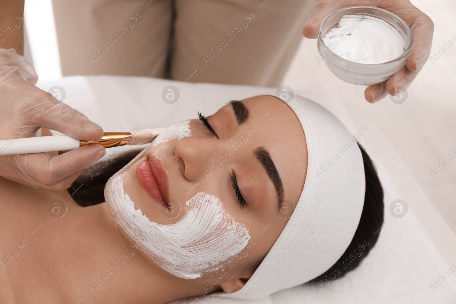 Photo of Young woman during face peeling procedure in salon