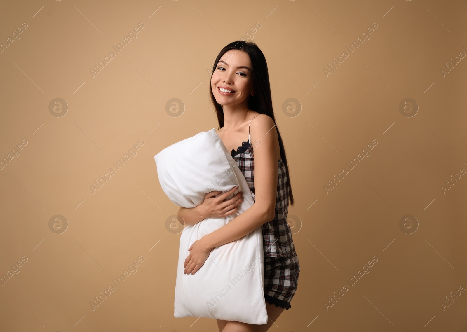 Photo of Beautiful Asian woman with pillow on beige background. Bedtime