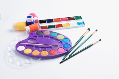 Photo of Set of paints and brushes on white background. Artistic equipment for children