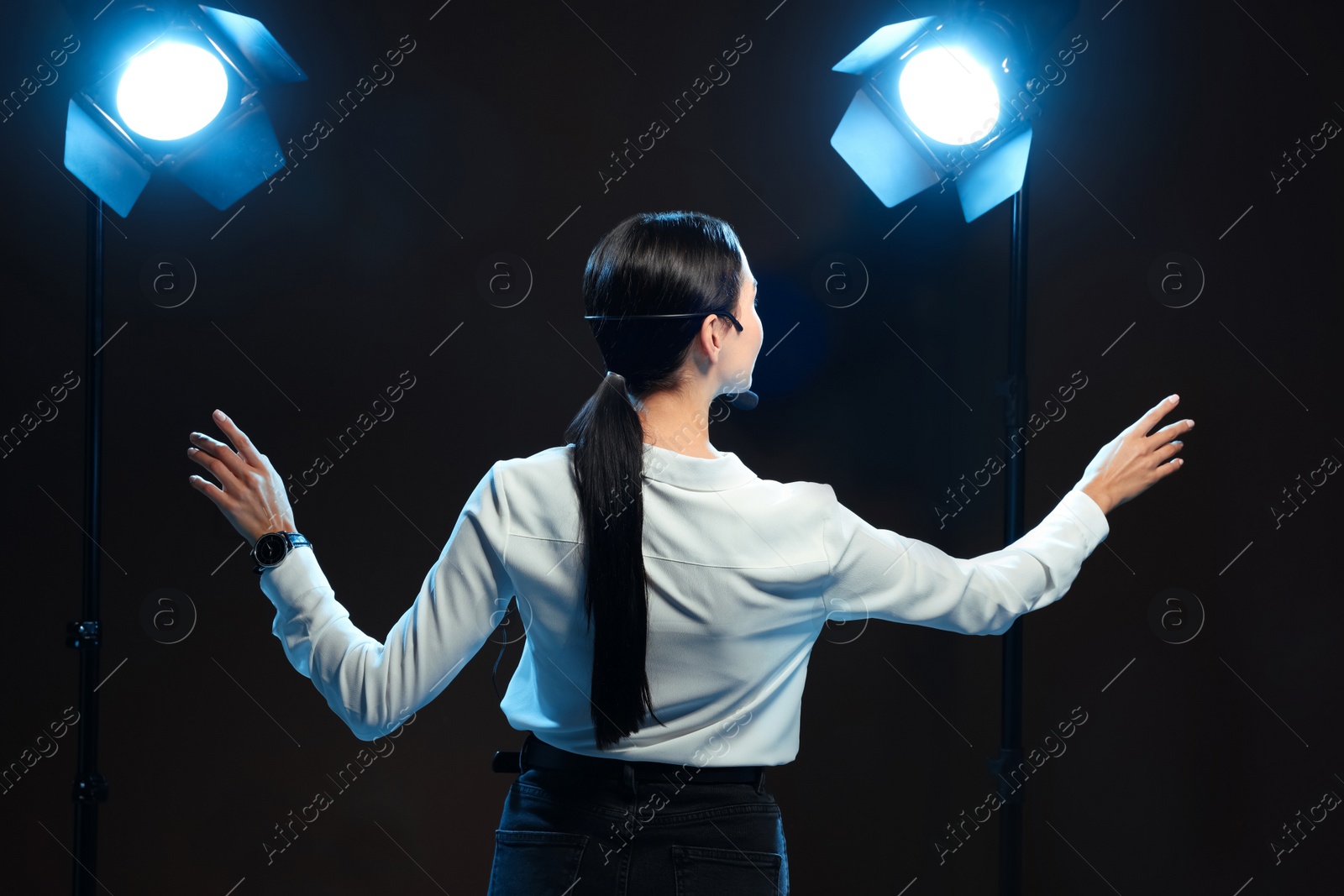 Photo of Motivational speaker with headset performing on stage, back view