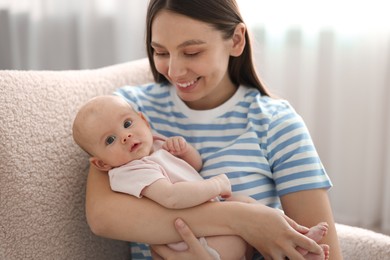 Photo of Mother with her cute baby in armchair at home