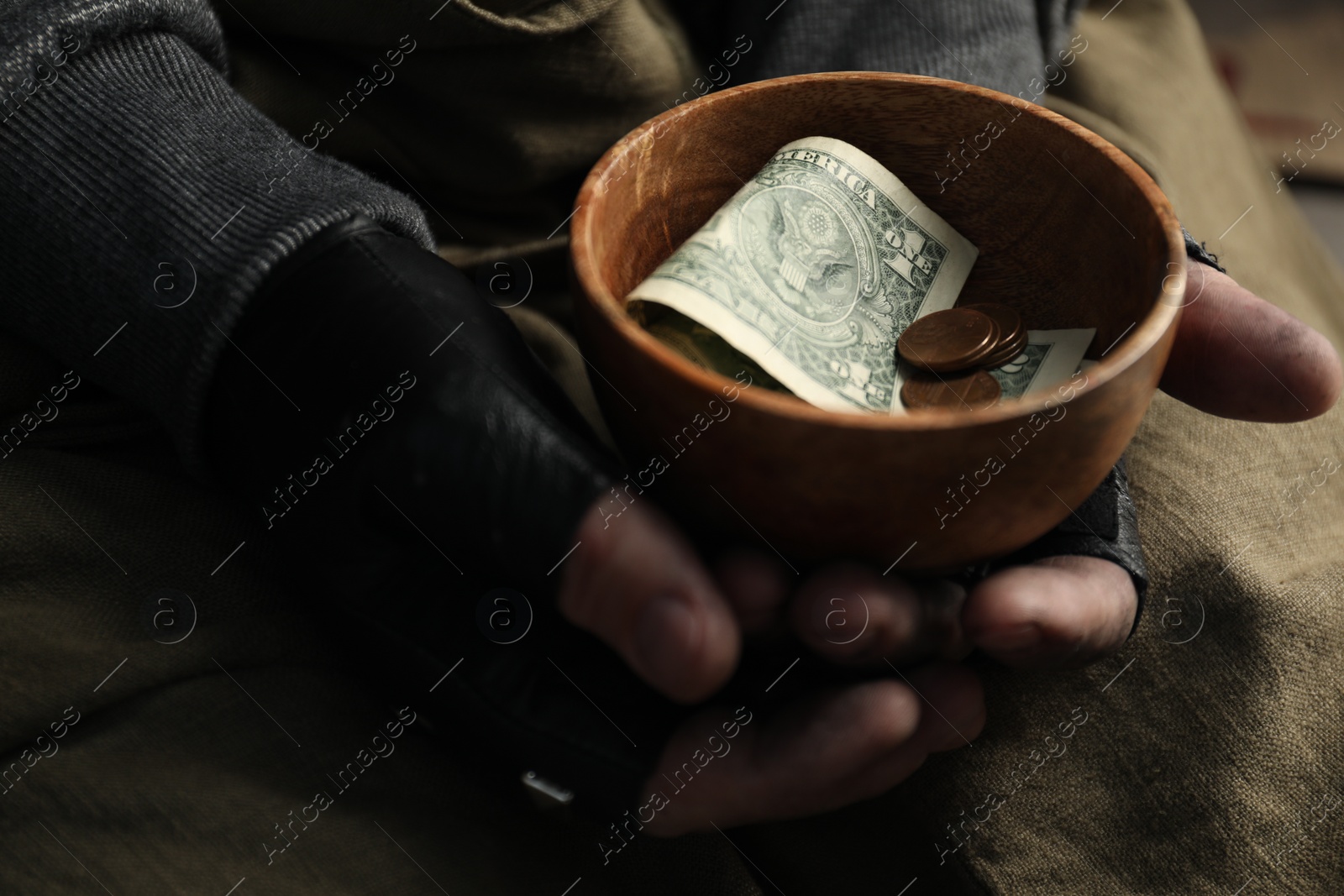 Photo of Poor homeless man holding bowl with donations, closeup