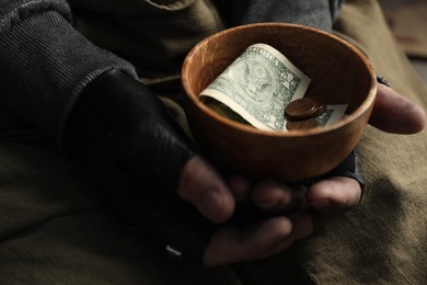 Photo of Poor homeless man holding bowl with donations, closeup