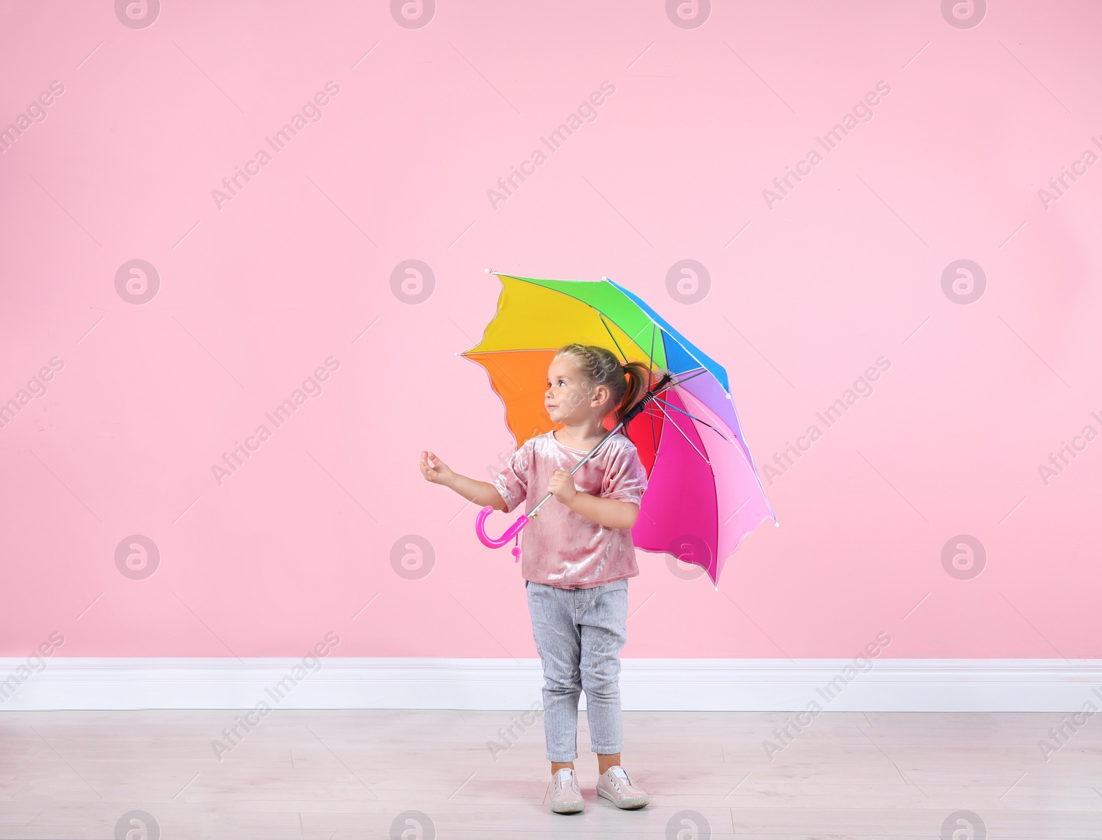 Photo of Little girl with rainbow umbrella near color wall