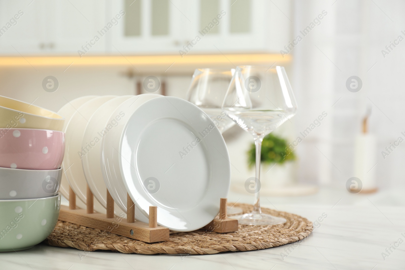 Photo of Clean plates, bowls and glasses on white marble table in kitchen, space for text