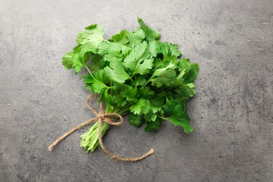 Photo of Bunch of fresh coriander on gray textured table, top view