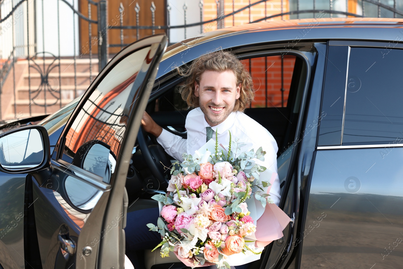 Photo of Young handsome man with beautiful flower bouquet in car