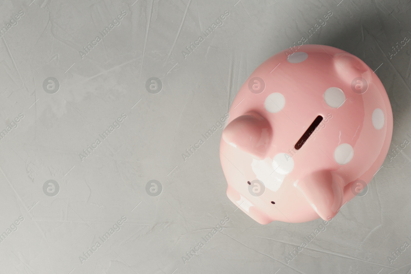 Photo of Ceramic piggy bank on light grey table, top view. Space for text