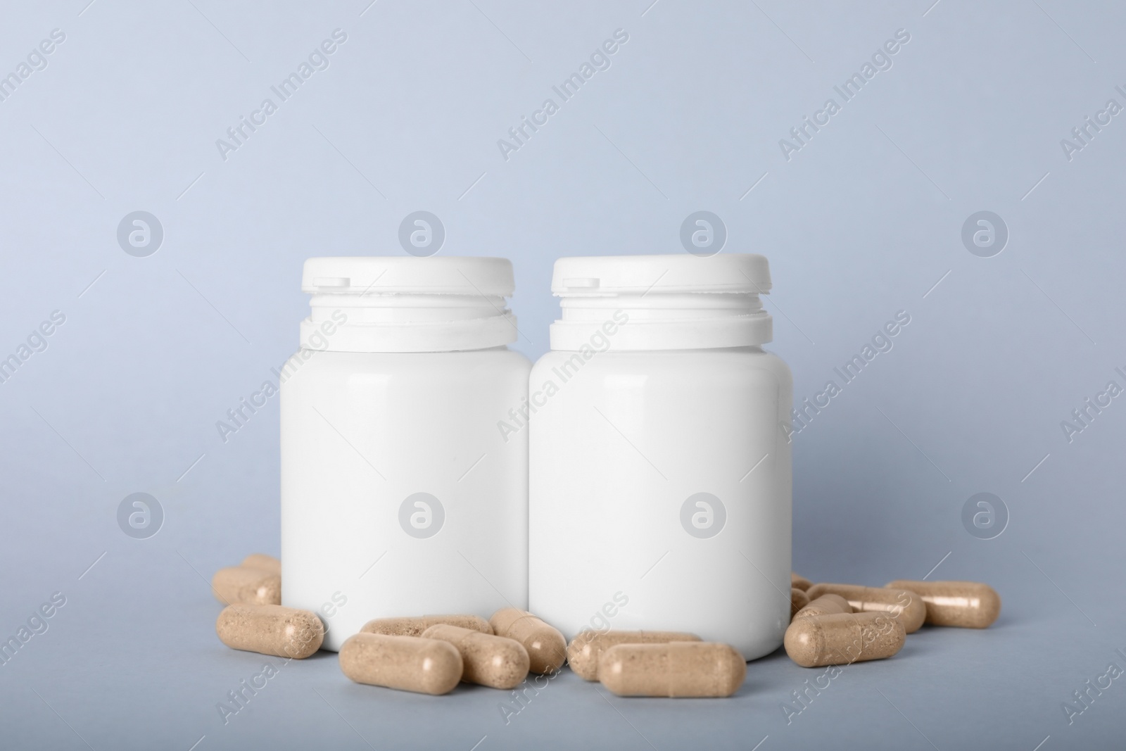 Photo of Gelatin capsules and bottles on light grey background
